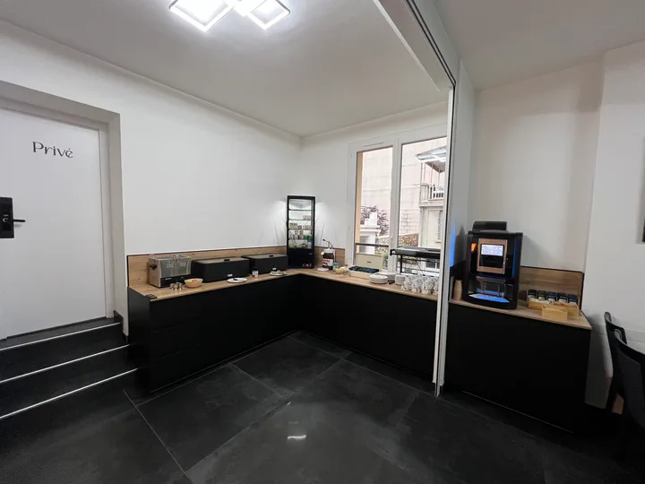 Salle du petit-déjeuner avec buffet continental, machine à café et tables dressées